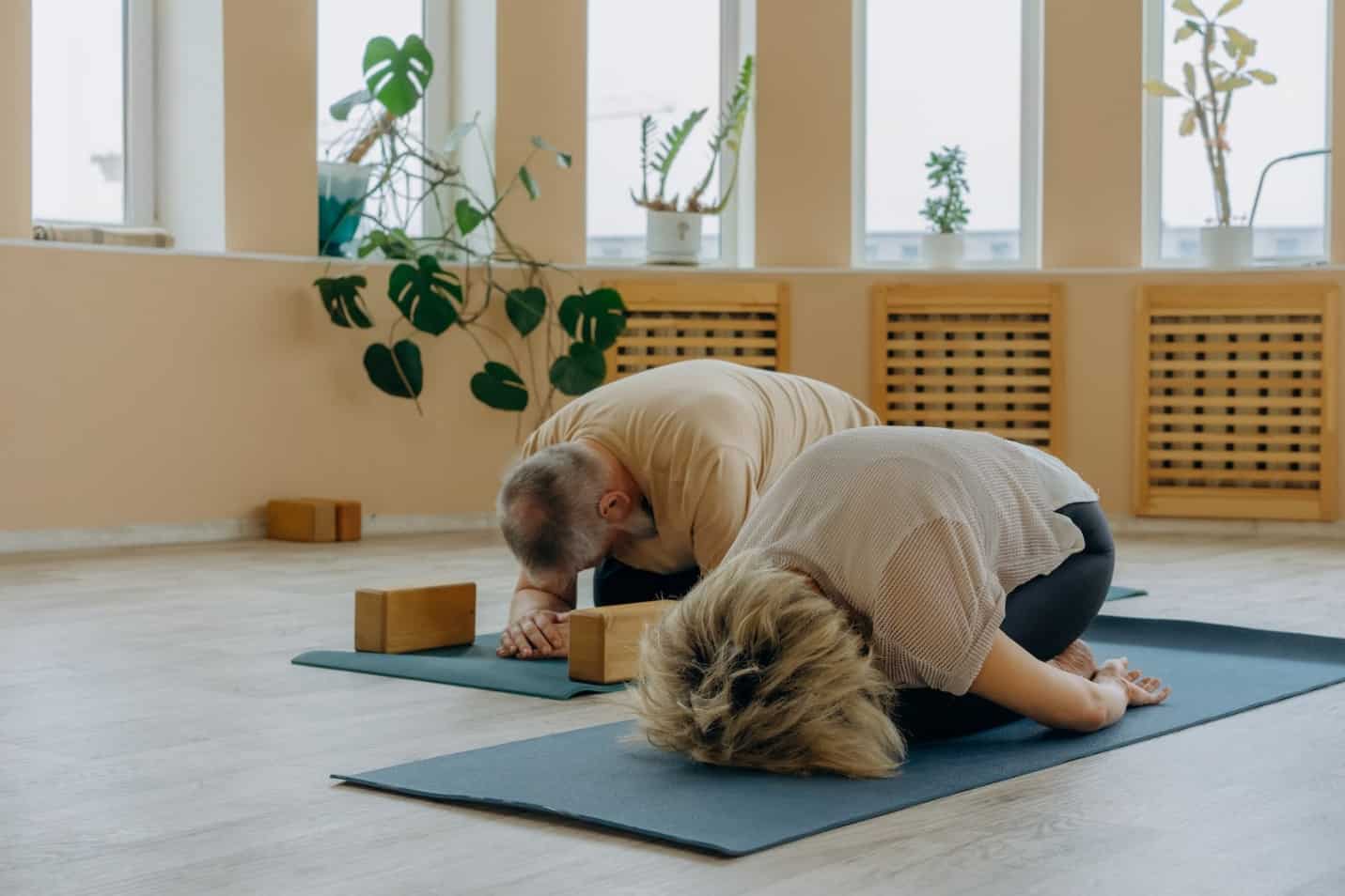Mature Couple in Child Yoga Pose on Mats with Blocks