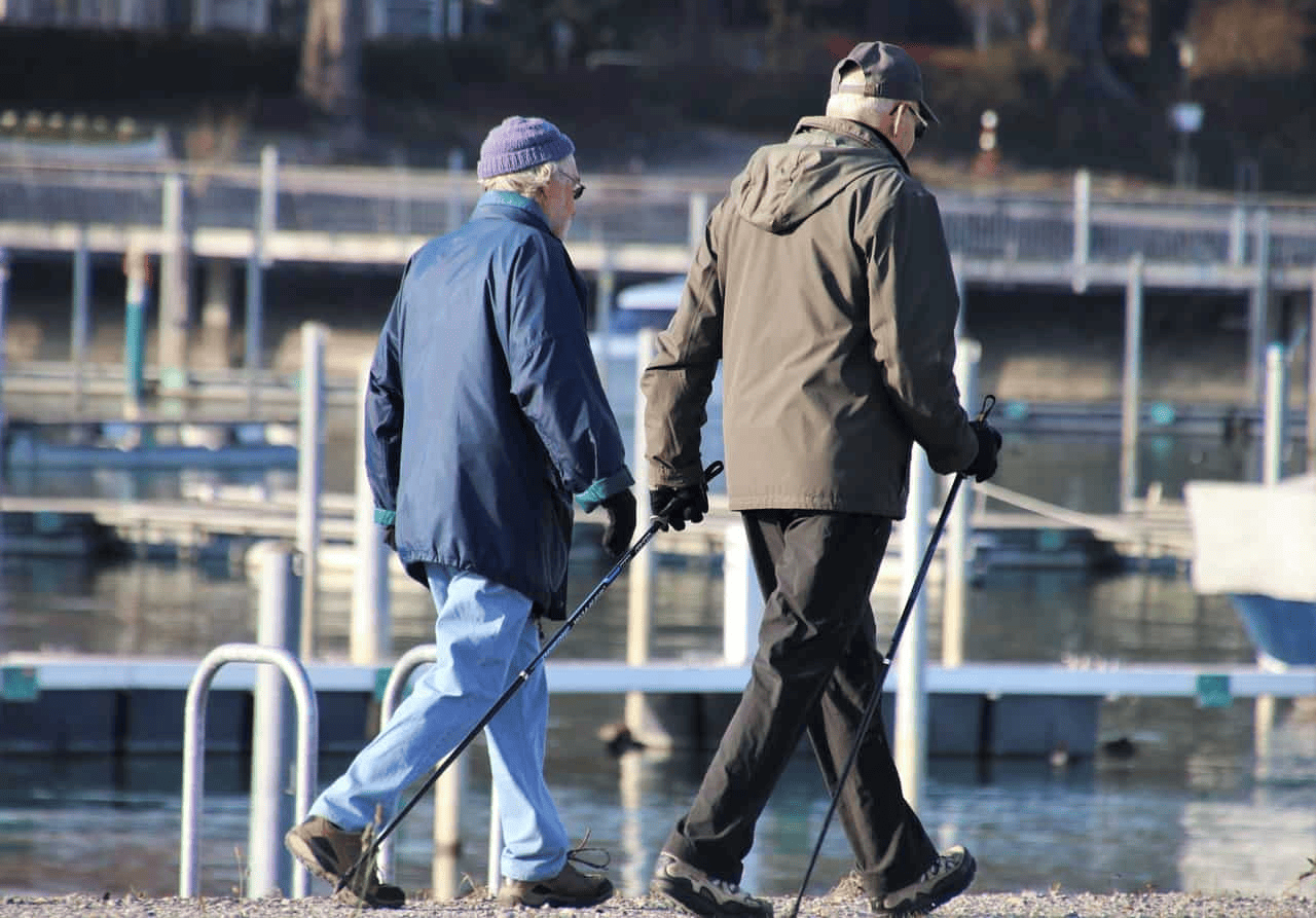 Two Men Walking Near Boat Dock with Walking Sticks