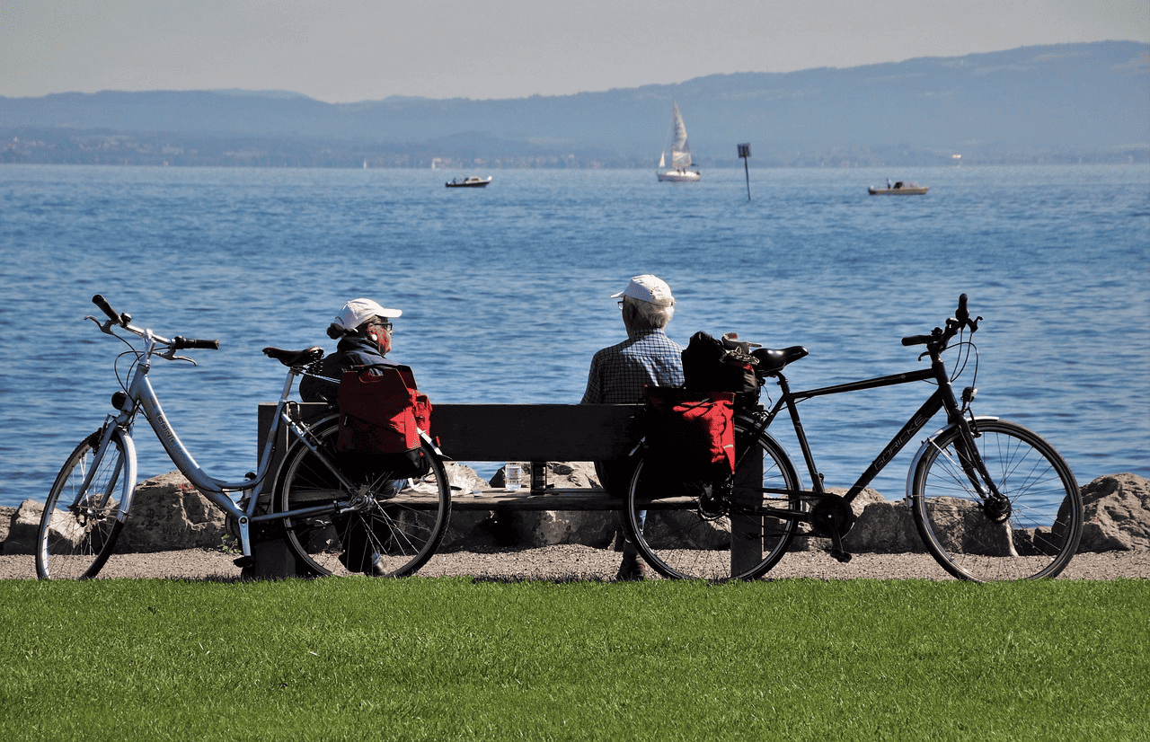 Two Older Males Relaxing on Bench Lakeside after Bike Ride
